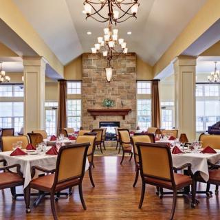 An elegant dining room with neatly set tables and a warm fireplace.
