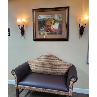 A cozy corner featuring a striped sofa and framed artwork, illuminated by stylish wall sconces.