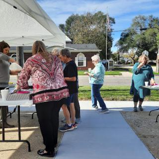 Community members enjoying a sunny day while participating in a food distribution event.