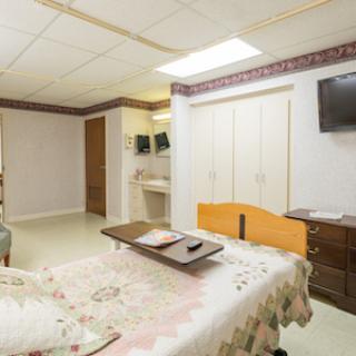 A well-lit and spacious hospital room equipped with essential furniture for patient care.