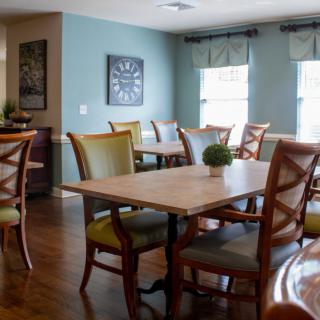 A cozy dining room with wooden tables and chairs, accented by decorative plants.