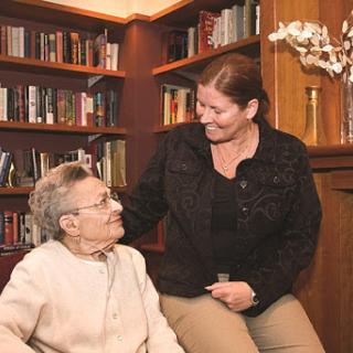 A caregiver sharing a warm moment with an elderly person in a cozy library setting.