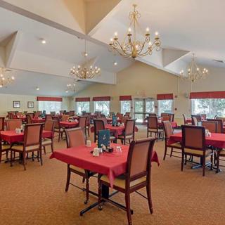 A spacious restaurant dining area with neatly arranged tables and elegant chandeliers.