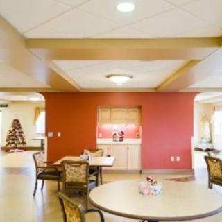 A spacious dining area with tables and chairs, featuring a red accent wall.