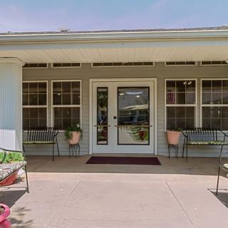 A welcoming building entrance with benches and potted plants on a sunny day.