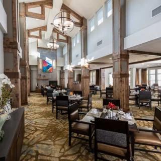 A spacious and elegantly designed restaurant interior with set tables and chairs.