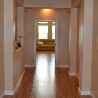 A hallway with wooden flooring leading to a living room.