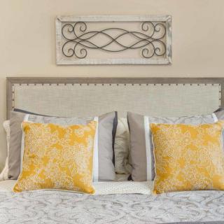 A stylish bedroom setup featuring a bed with yellow decorative pillows and a sophisticated headboard.