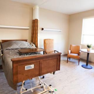 A clean and well-lit hospital room with a bed and seating area.