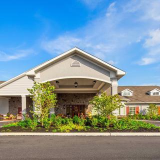A beautiful building with a landscaped garden and welcoming entrance under a blue sky.