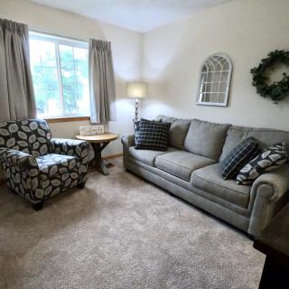 A cozy living room featuring a sofa, armchair, and decorative elements.