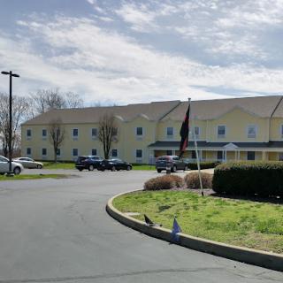 A view of a hotel building with cloudy skies above and vehicles parked in the lot.