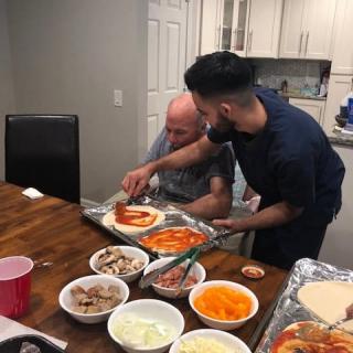 Two people making homemade pizzas together in the kitchen.
