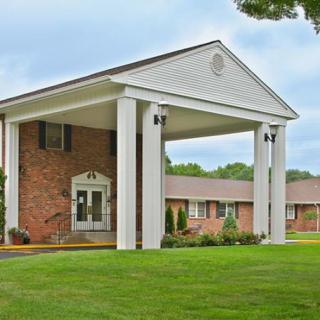 A brick building with a prominent entrance featuring white columns and a covered walkway.