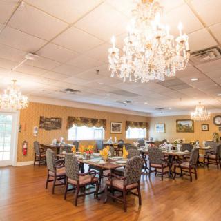 An elegant dining room with chandeliers, set for a meal.