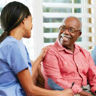 A nurse engaging in a friendly conversation with an elderly man.