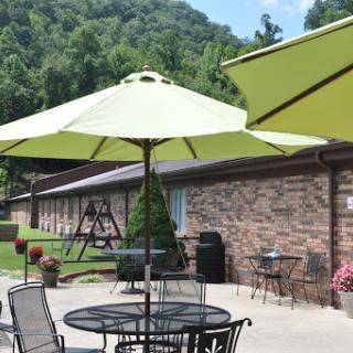 A serene outdoor patio area with green umbrellas and a scenic backdrop.