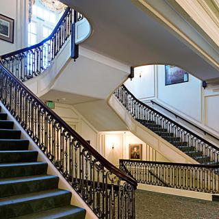 An elegant interior staircase with a decorative balustrade in a hotel.