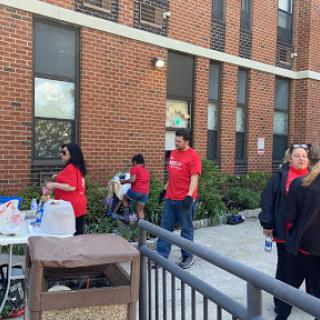 A community gathering featuring individuals in red shirts outside a brick building.