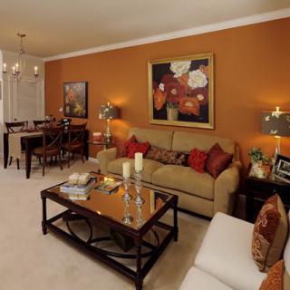 A cozy living room with warm colors, featuring a sofa, coffee table, and adjacent dining area.