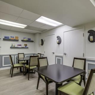 A neat and well-lit dining area with tables and chairs, featuring decorative elements on the walls.