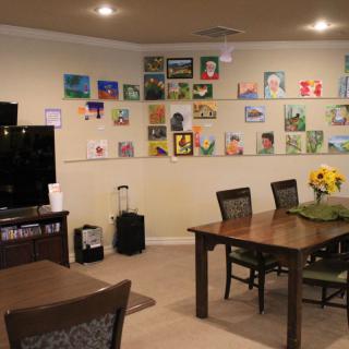 A cozy living room with a dining area and a vibrant display of artwork on the wall.