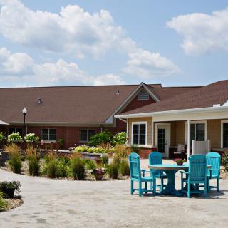 A charming house with a garden patio featuring outdoor seating under a blue sky with clouds.