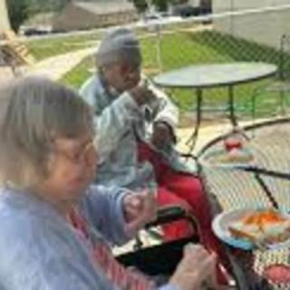 Two elderly individuals enjoying a meal outdoors at a park table.
