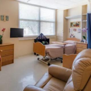A well-lit hospital room with a bed, TV, and reclining chair.