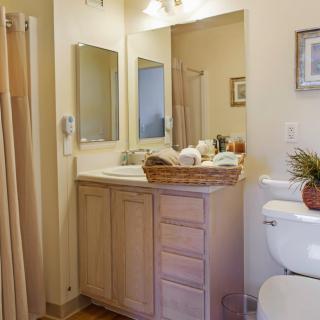 A tidy and well-organized bathroom with a vanity, mirror, and shower.