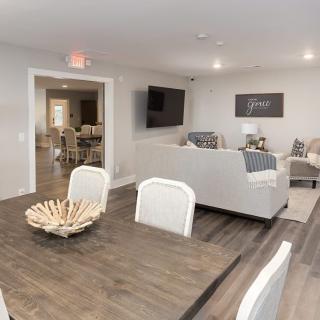 A modern living room with a dining area, featuring neutral-colored furniture and a wooden table.