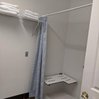 A minimalist bathroom shower area with neatly arranged towels and a simple curtain.