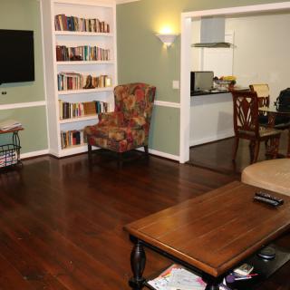 A cozy living room with a bookshelf, armchair, and TV on a wooden floor.