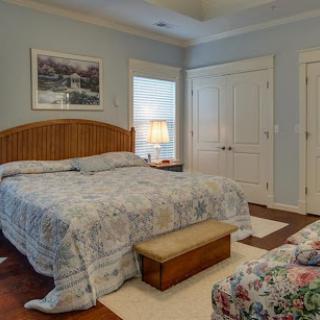 A cozy and serene bedroom featuring a large bed with floral bedding and a wooden bench at the foot.
