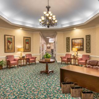 A warmly lit lobby area with a chandelier, seating arrangements, and decorative elements.