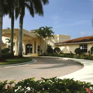 A beautiful building with palm trees and a circular driveway.