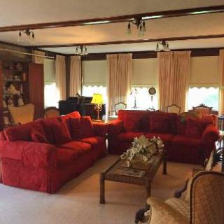 A cozy living room featuring plush red sofas and ample natural light.