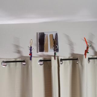 A cozy home setting featuring beige curtains adorned with colorful clothespins and a decorative photo above them.