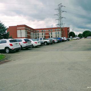 A view of a parking lot beside a building under a cloudy sky.