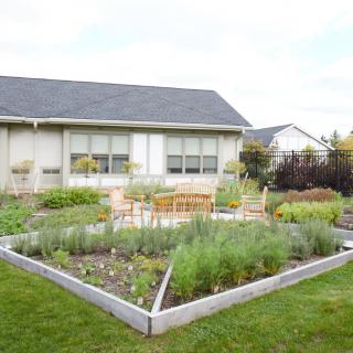 A well-maintained backyard with raised garden beds in front of a house.