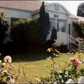 A quaint house surrounded by a lush garden and blooming flowers.