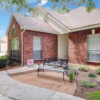 A charming brick house with a small front yard and a bench by the pathway.