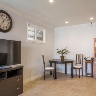 A cozy living room with a television and a small dining table set.