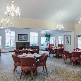 A spacious dining room with elegant chandeliers and neatly arranged tables and chairs.