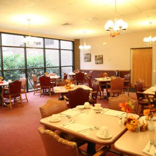 A spacious dining area filled with tables and chairs, offering a cozy atmosphere with ample natural light.
