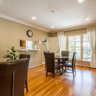 A cozy dining room with a wooden table set, large window, and warm lighting.