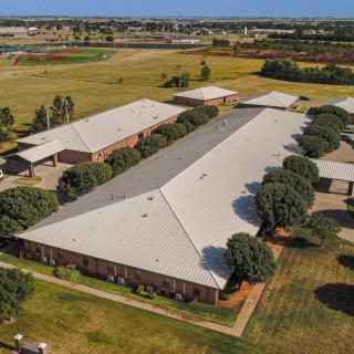 Aerial view of a large building surrounded by trees in a rural landscape.