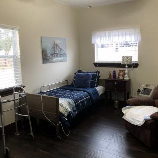 A small bedroom with a single bed, nightstand, and a reclining chair.