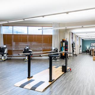 A spacious physical therapy studio featuring exercise equipment and ballet bars for rehabilitation and fitness activities.