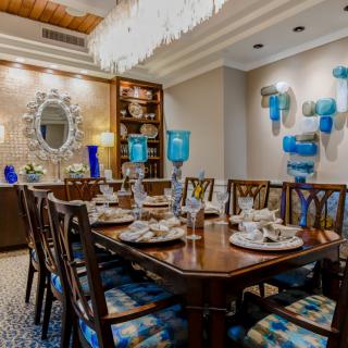A luxurious dining room with elegant decor, featuring a large wooden table, stylish chairs, and blue accents.